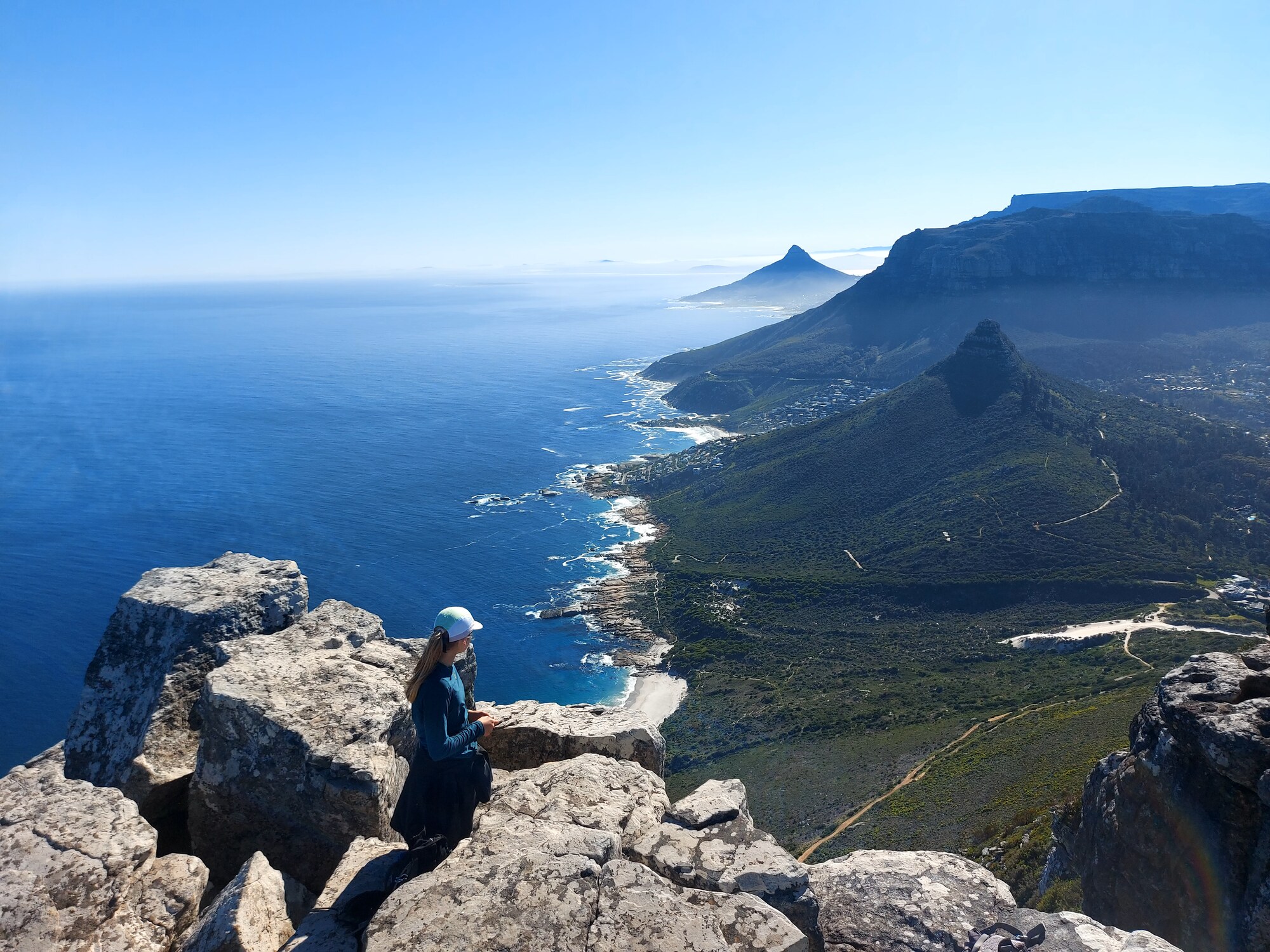 Hiker overlooking the Atlantic coastline from rocky terrain on Cape Town's 13 Peaks route